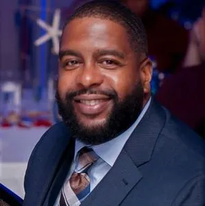 A man in a suit and tie smiling for the camera.