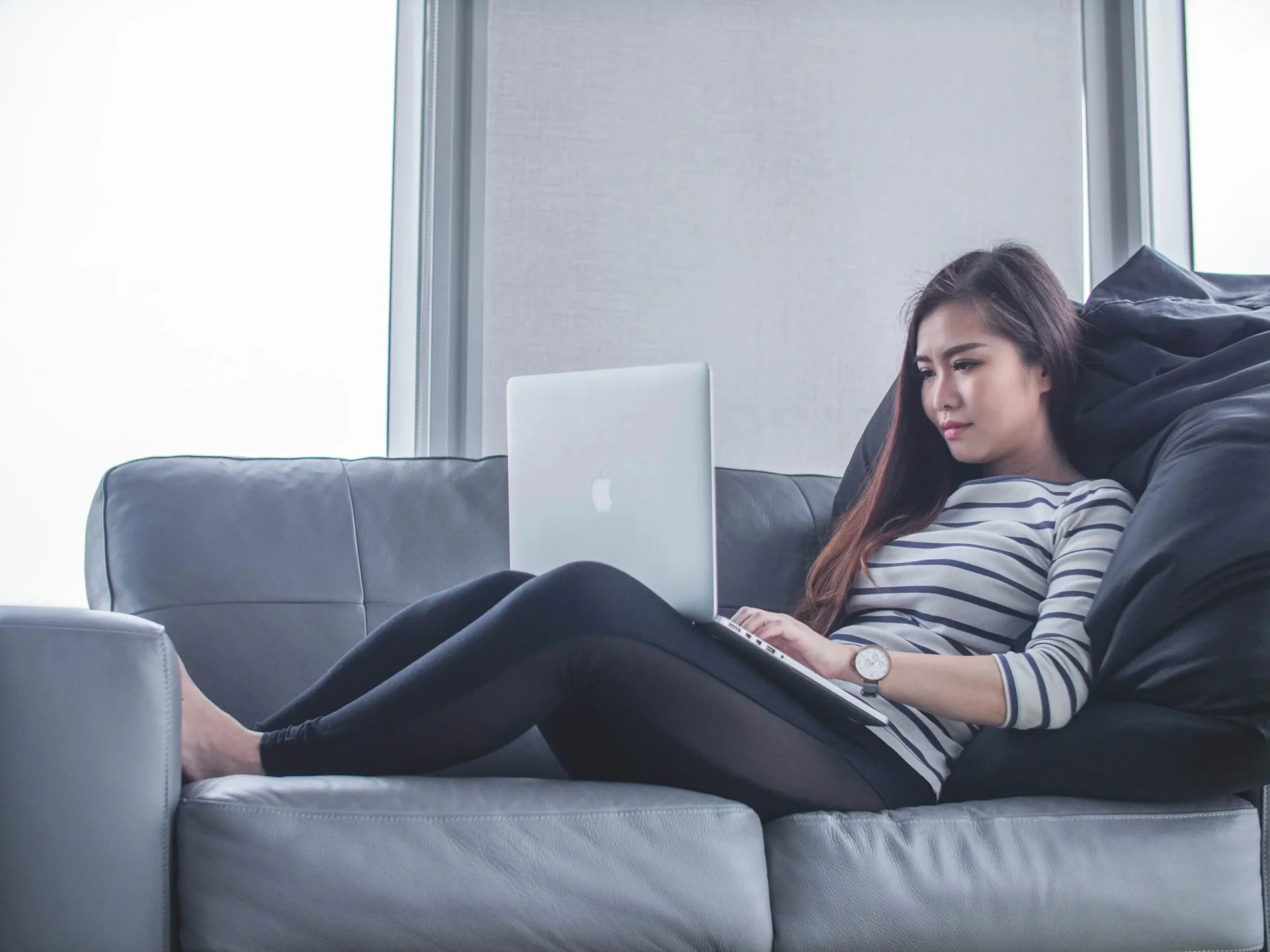 A woman is sitting on the couch with her laptop.