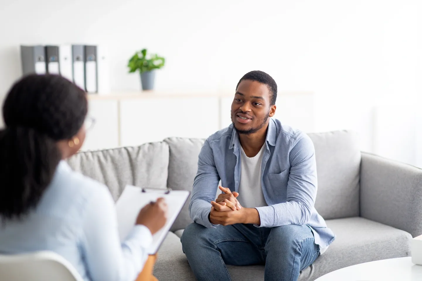 A man sitting on top of a couch talking to someone.